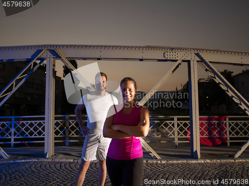 Image of portrait of couple jogging across the bridge in the city