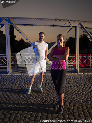 Image of portrait of couple jogging across the bridge in the city