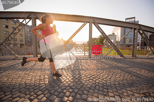 Image of woman jogging across the bridge at sunny morning