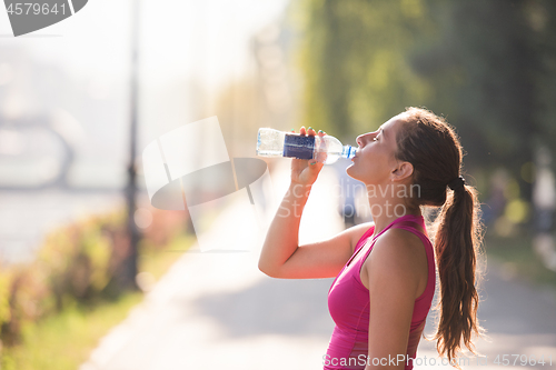 Image of woman drinking water from a bottle after jogging
