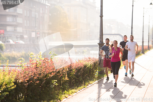 Image of group of young people jogging in the city