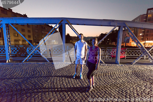 Image of couple jogging across the bridge in the city