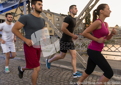 Image of group of young people jogging across the bridge