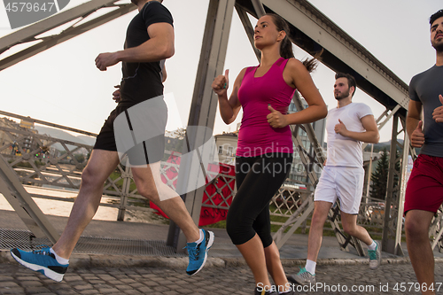 Image of group of young people jogging across the bridge