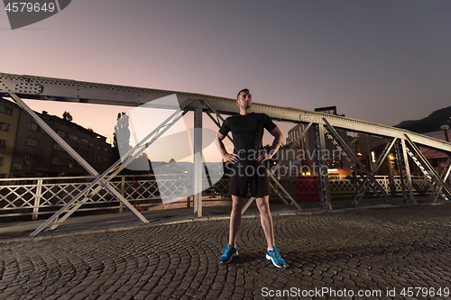 Image of man jogging across the bridge in the city