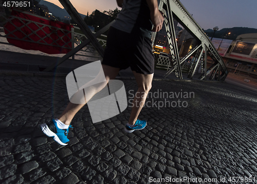 Image of man jogging across the bridge in the city