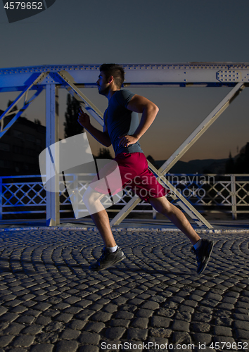 Image of man jogging across the bridge in the city