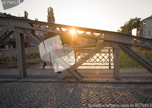 Image of woman jogging across the bridge at sunny morning