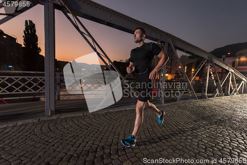 Image of man jogging across the bridge in the city