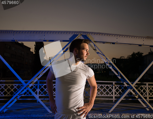 Image of man jogging across the bridge in the city