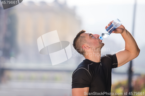 Image of man drinking water from a bottle after jogging