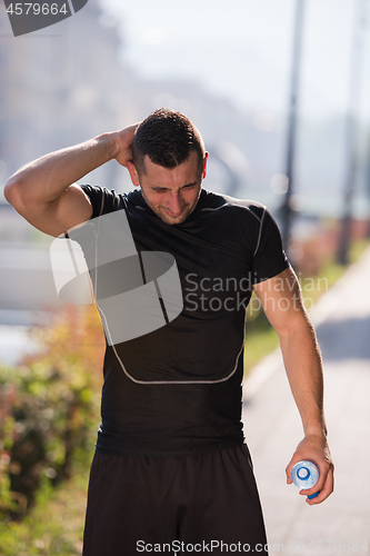 Image of man pouring water from bottle on his head