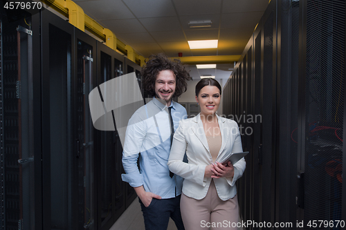 Image of engineer showing working data center server room to female chief