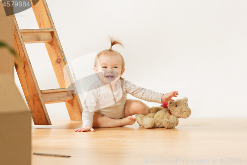 Image of Friendly blue eyed baby girl sitting on the floor indoors