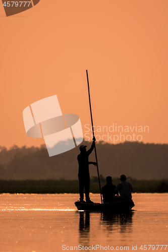 Image of Men in a boat on a river silhouette