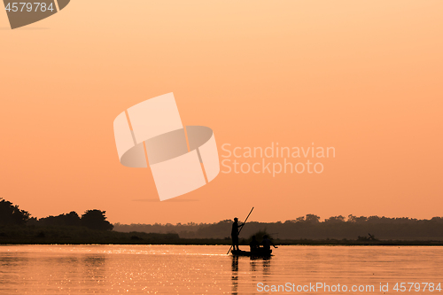 Image of Men in a boat on a river silhouette