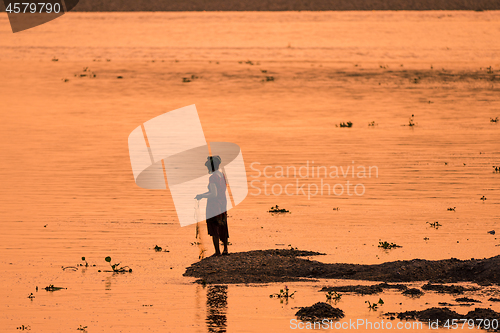 Image of Asian Woman fishing in the river, silhouette at sunset