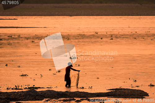 Image of Asian Woman fishing in the river, silhouette at sunset