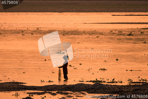 Image of Asian Woman fishing in the river, silhouette at sunset