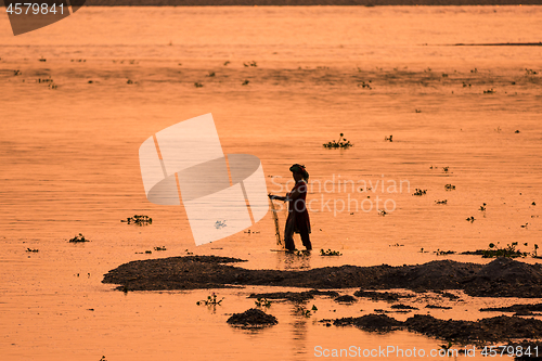 Image of Asian Woman fishing in the river, silhouette at sunset