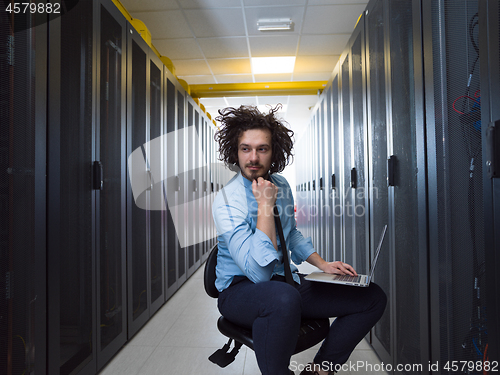 Image of engineer working on a laptop in server room