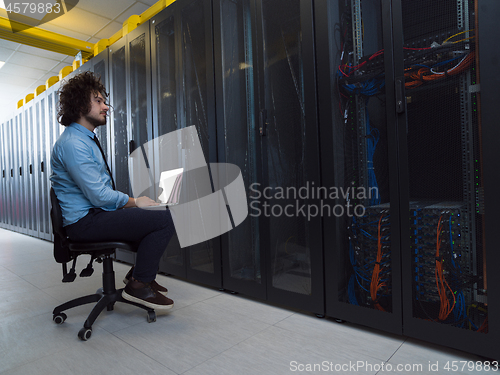 Image of engineer working on a laptop in server room