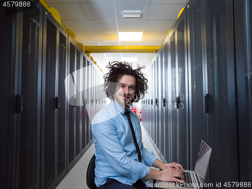 Image of engineer working on a laptop in server room