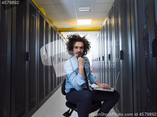 Image of engineer working on a laptop in server room