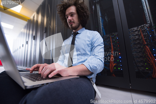 Image of engineer working on a laptop in server room