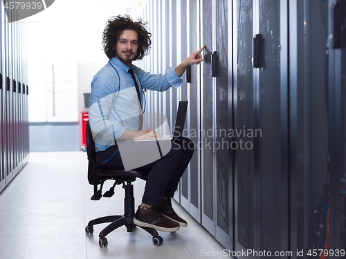 Image of engineer working on a laptop in server room