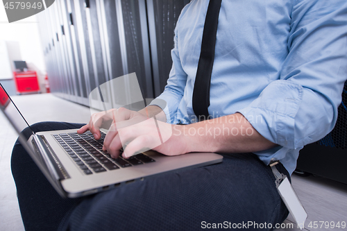 Image of engineer working on a laptop in server room