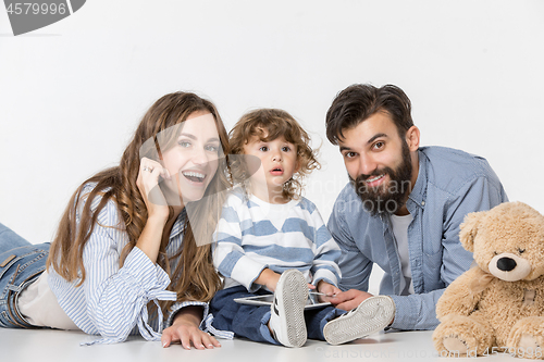 Image of Smiling family sitting together in studio and watching their favorite cartoons on laptop