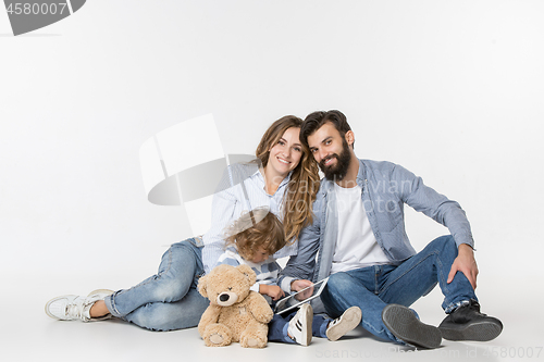 Image of Smiling family sitting together in studio and watching their favorite cartoons on laptop