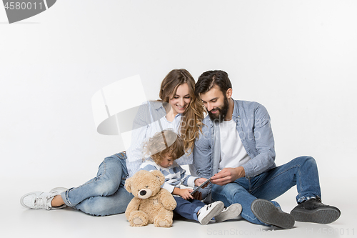 Image of Smiling family sitting together in studio and watching their favorite cartoons on laptop