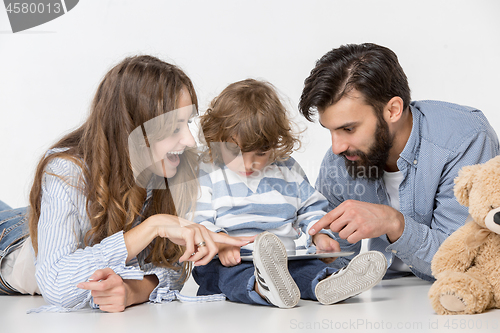 Image of Smiling family sitting together in studio and watching their favorite cartoons on laptop