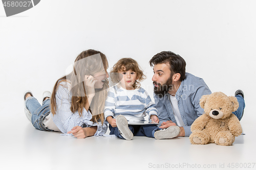 Image of Smiling family sitting together in studio and watching their favorite cartoons on laptop