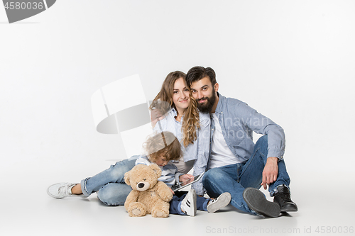 Image of Smiling family sitting together in studio and watching their favorite cartoons on laptop