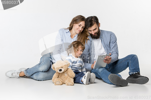 Image of Smiling family sitting together in studio and watching their favorite cartoons on laptop