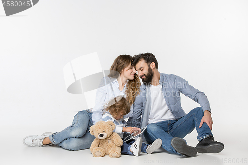 Image of Smiling family sitting together in studio and watching their favorite cartoons on laptop