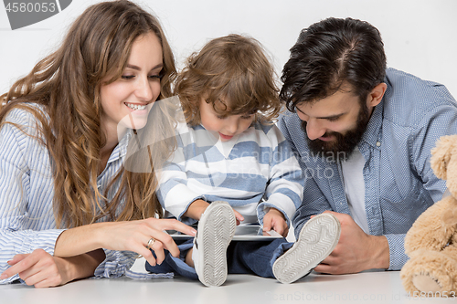 Image of Smiling family sitting together in studio and watching their favorite cartoons on laptop