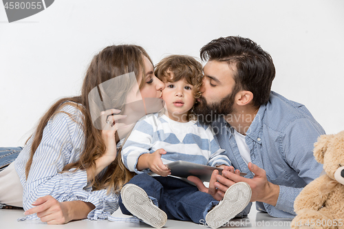 Image of Smiling family sitting together in studio and watching their favorite cartoons on laptop