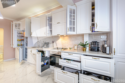 Image of Modern white kitchen interior with open doors and drawers