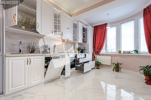 Image of Luxury modern white kitchen interior with open doors and drawers