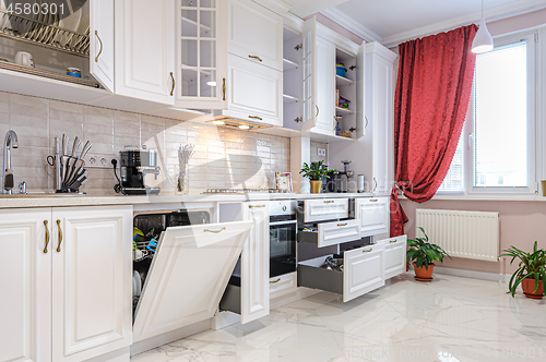 Image of Luxury modern white kitchen interior with open doors and drawers