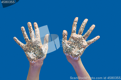 Image of Woman\'s hands with holiday decoration glitter small stars on a blue.