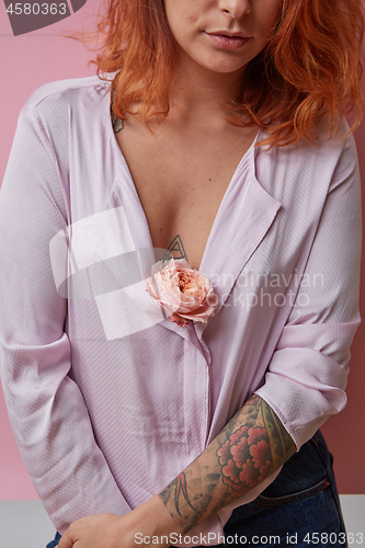Image of Sexual  girl with fresh flower living coral color in hands with tattoo on a gray background. 
