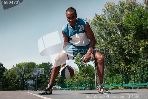 Image of Picture of young confused african basketball player practicing