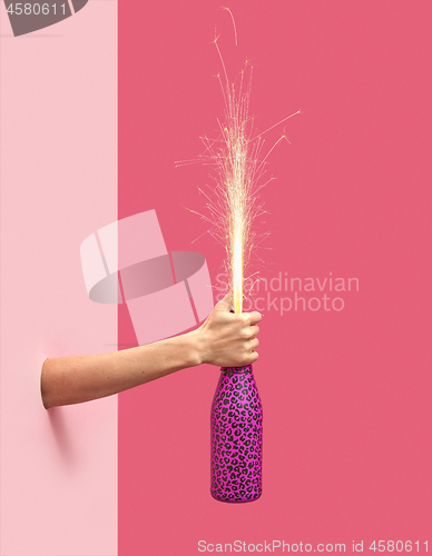 Image of Holiday firework in a painted bottle in a female\'s hand.