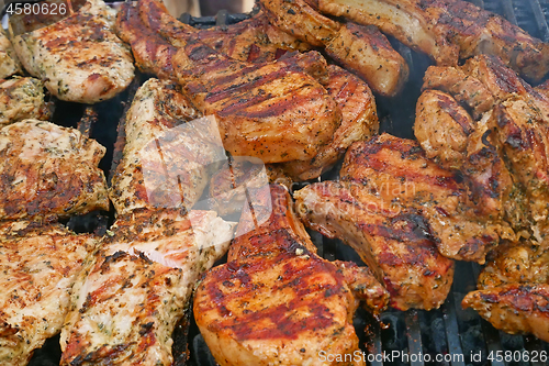 Image of A lot of pieces of meat are roasted on metal bars