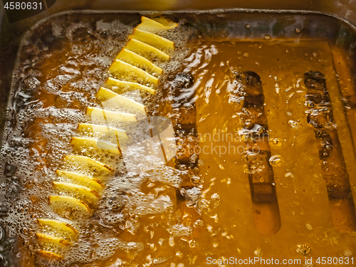 Image of Potato slices are fried in oil in a deep fryer